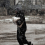 A Syrian woman runs under the snow after