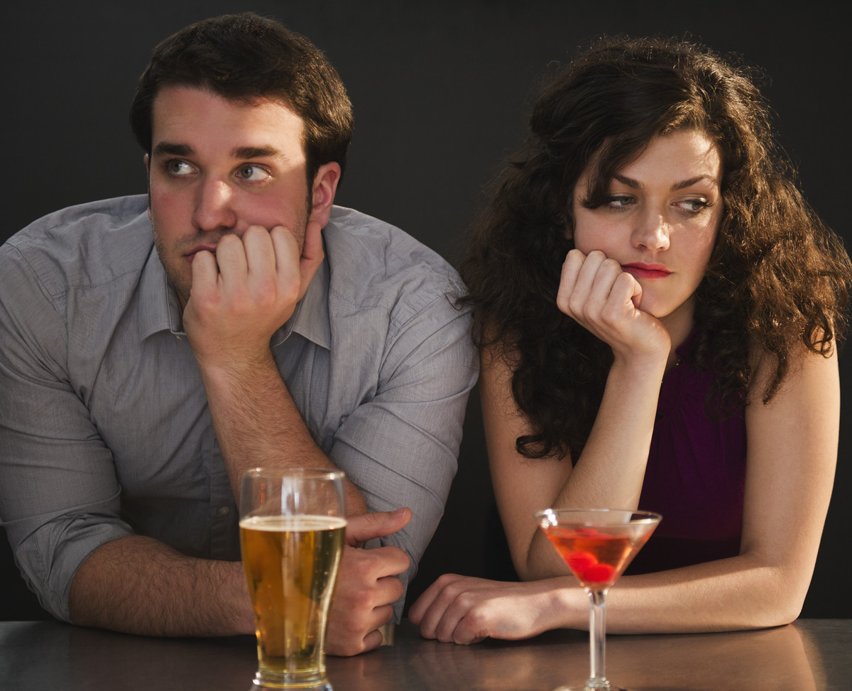 Man and woman sitting at a bar ignoring each other