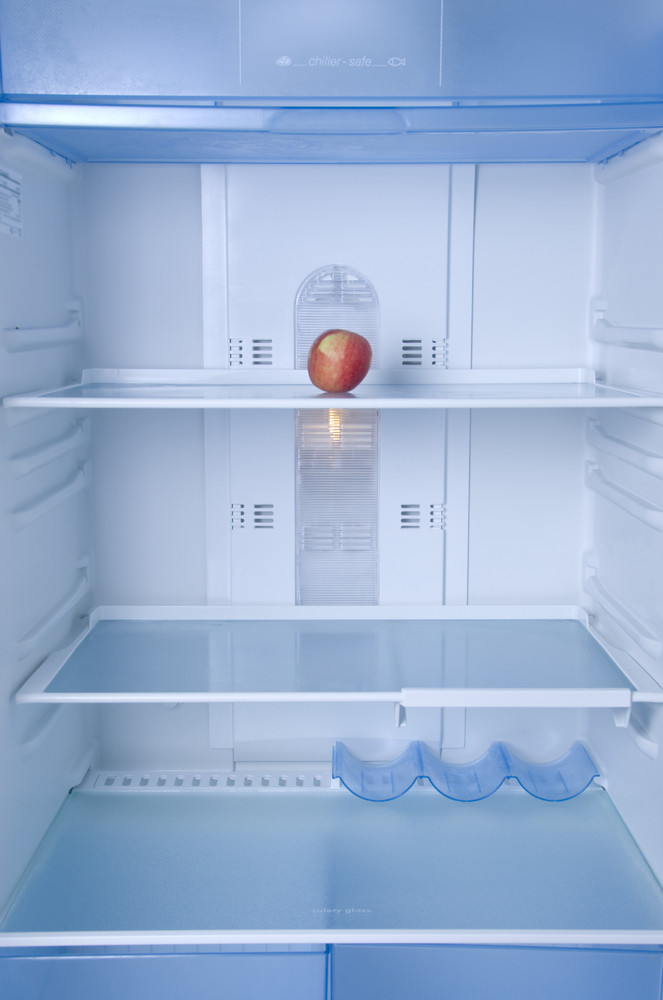 Empty fridge with only an apple on the shelf