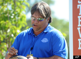 Steve McMichael autographs a football as he stands on the float at the