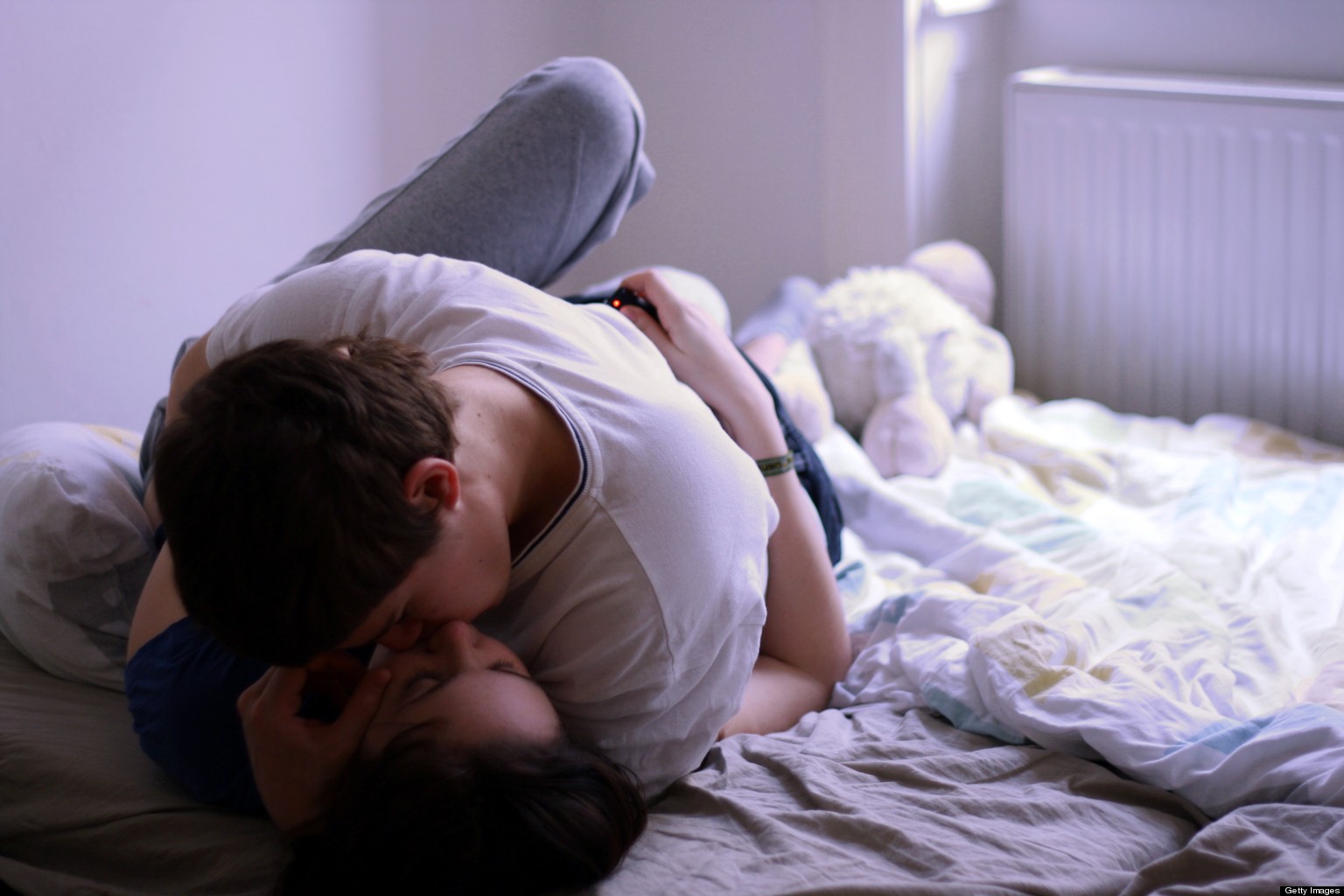 Девушка и парень на кровати целуются