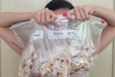 Celebrity holding bags of pills