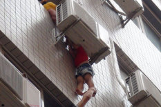 Boy hanging from air conditioning unit