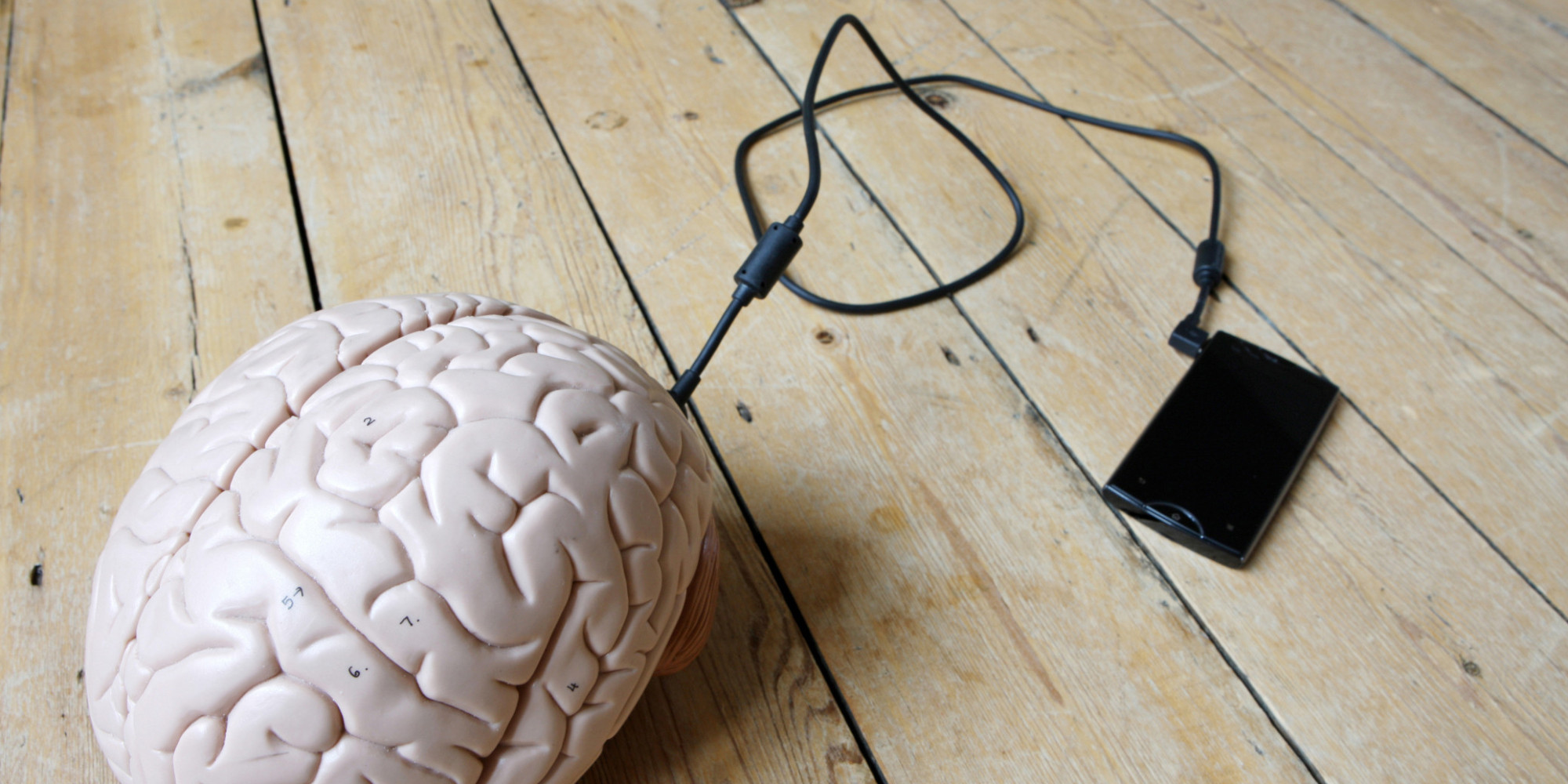 Image of a smartphone with a cord plugged into a brain