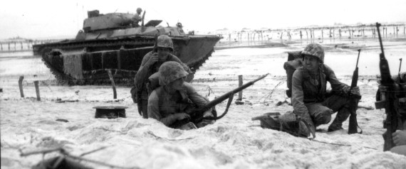 MARINES MOVING ALONG THE BEACH CAUTIOUSLY WHILE AN