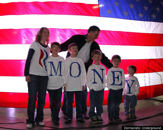 Mitt Romney standing in front of an American flag with a group of boys wearing tshirts that spell out MONEY