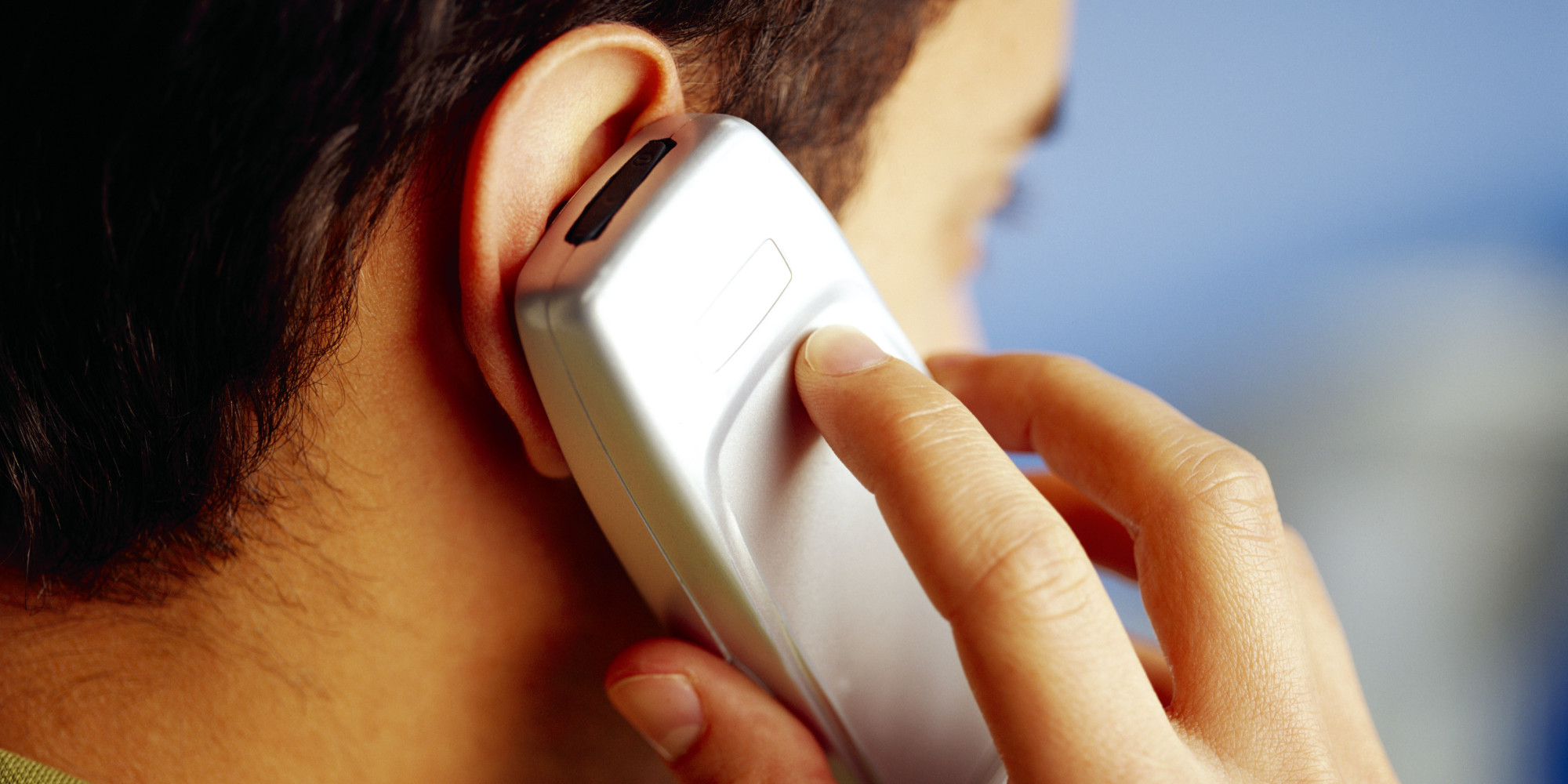 Close of a man talking on an older style mobile phone.