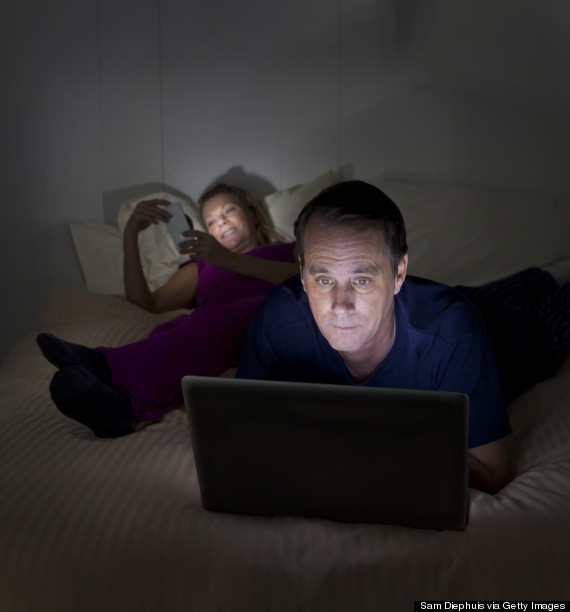 couple on computers in bed