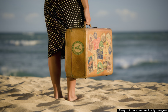 person standing on beach with luggage