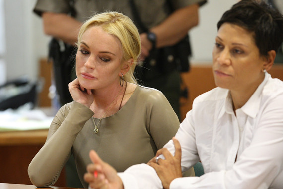 Lindsay Lohan in court with her lawyer looking at her writing down something.